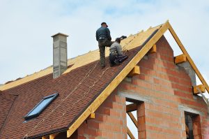 Roofing Construction and Building New Brick House with Modular Chimney Skylights Attic Dormers and Eaves Exterior. Roofers Install Repair Asphalt Shingles or Bitumen Tiles on the Rooftop Outdoor. Residential skylight solutions