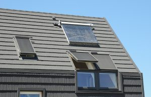 Modern attic roof with solar panels, skylights and blinds window for sun protection and house energy efficiency.